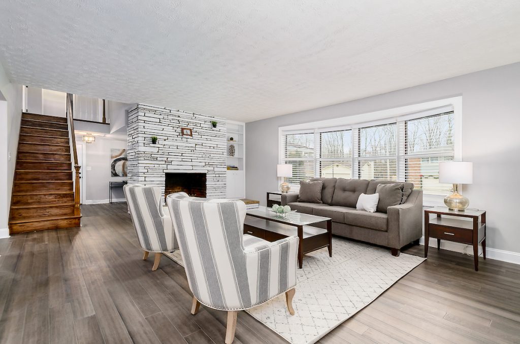 Revitalizing Neighborhoods, One House At A Time 15 A lovely living room with luxurious chairs, a staircase, and a white rug.