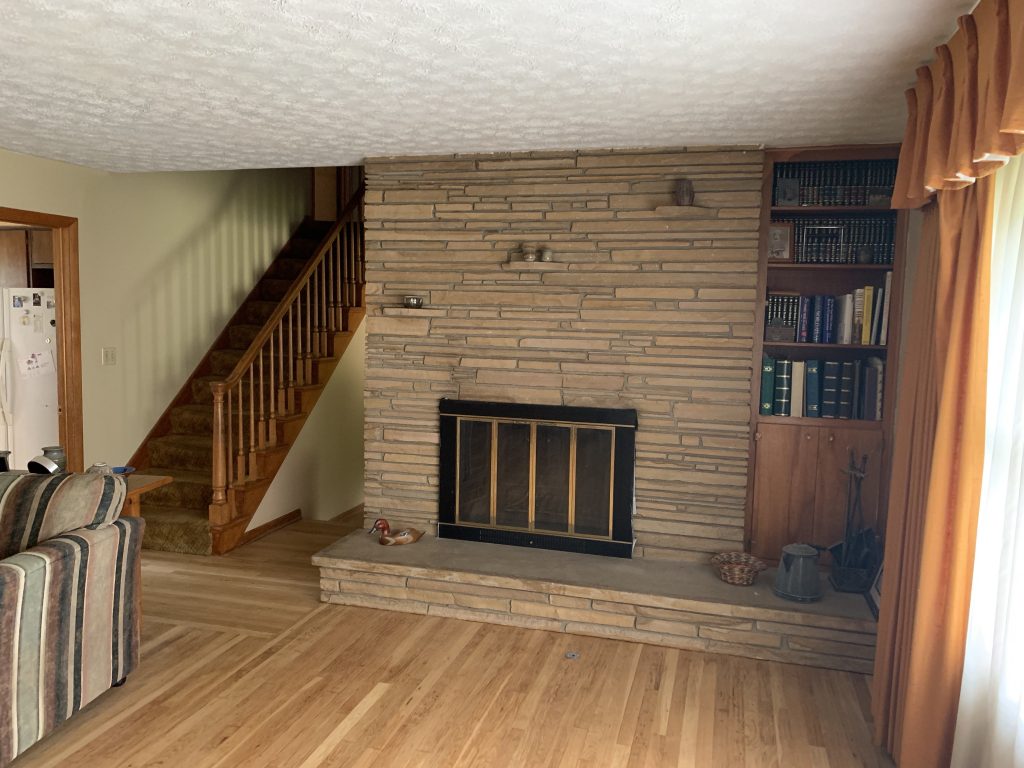Revitalizing Neighborhoods, One House At A Time 13 A living room hearth and wooden staircase.