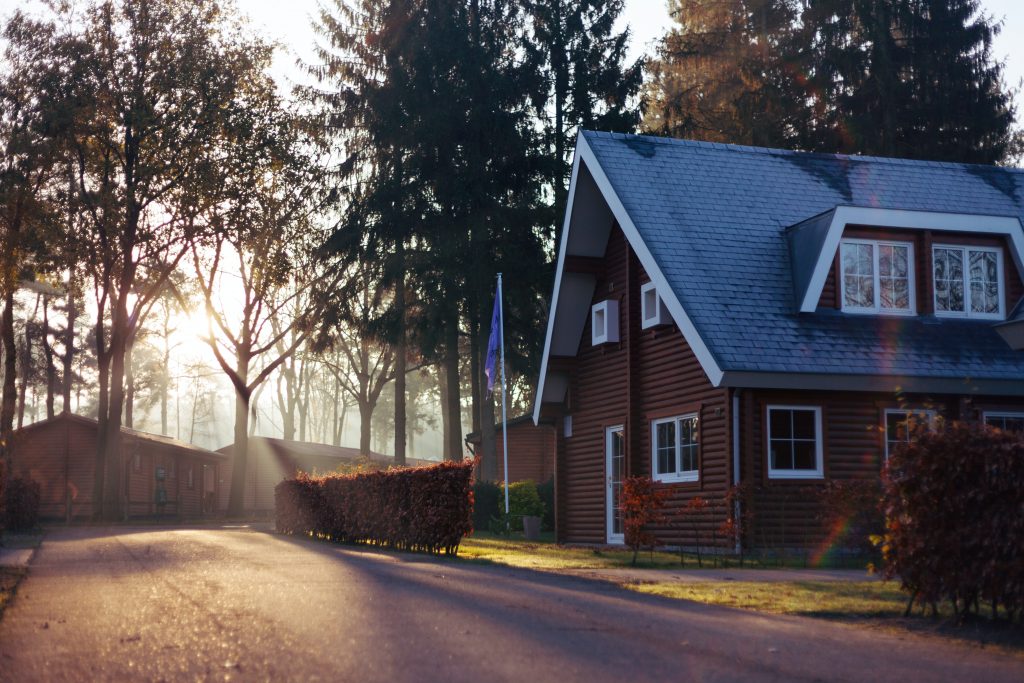 The 5 Biggest Home Renovation Costs to Sell a Home 2 A beautiful home by a road surrounded by bushes and trees with a flag out front.