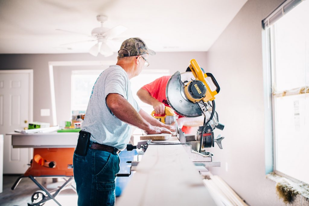 6 Great Ways to Lower Your Home Building Cost 2 Two builders showing how to build a house and using a yellow DeWalt saw to make cuts in materials.