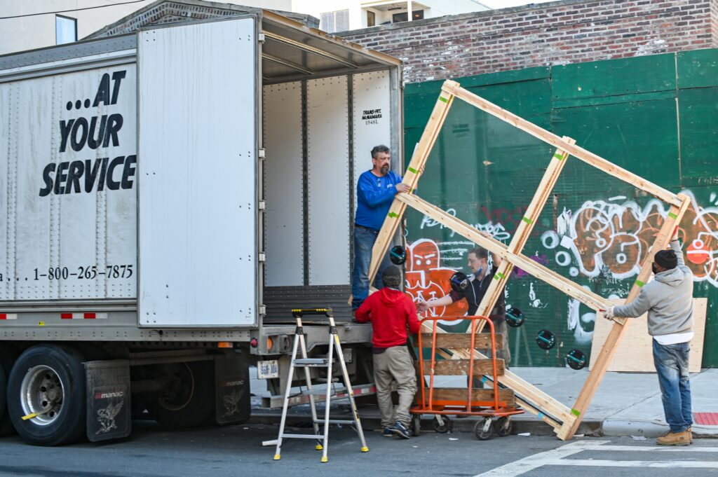 How to Prepare for a Move: Your 2021 Moving Checklist 1 Four movers load a wooden bed frame onto a moving truck.